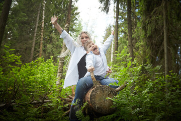 Funny mother with dreadlocks and fat boy happy hugging in the woods on a sunny summer day