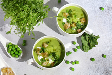 Cool Summer Pea Soup with Croutons, Sour Cream, Fresh Mint, Pea Sprouts, and Parsley Green Oil. Vegetarian Cuisine Idea. Artisanal Photography, Not AI
