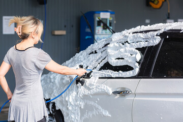 Woman washing car in a self-service car wash station
