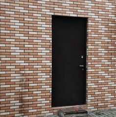 closed iron, metal door in yellow, brown brick wall. exterior of new, modern house. Steel door in a new brick wall. domestic background. front view