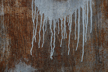 Messy paint streaks and smudges on an old painted wall. beige, silver, white color drips, flows, streaks flowing of paint and paint sprays. rusty, rust-eaten iron sheet background.