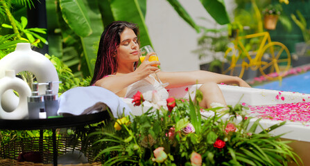 Asian Indian Hindu gen z happy relax woman cute lady sitting tub hold drink fresh juice glass...