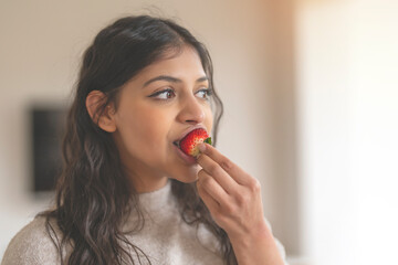 indian woman eating strawberry at home