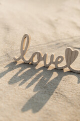 Wooden word love on sandy beach background. Concept of romantic holiday anniversary, proposal,...