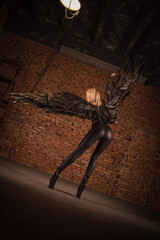 Beautiful girl a dark angel with black wings posing on the dark background. Angel of the night concept.