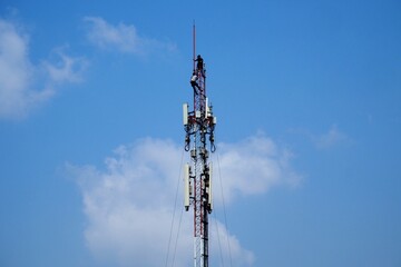 Technician working on Telecommunication Tower, blue sky background
