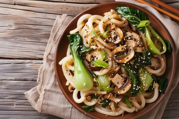 Top view of Asian vegetarian udon noodles with baby bok choy shiitake mushrooms sesame and pepper on a table