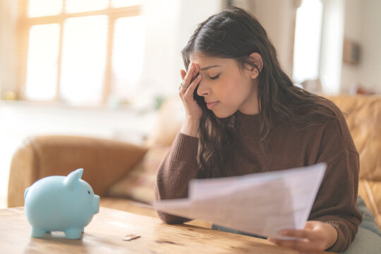 Worried young indian woman reading letter savings employment tax paying energy bill confused upset