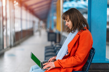 woman at railway station using computer, laptop. Working, studying, shopping, booking online....