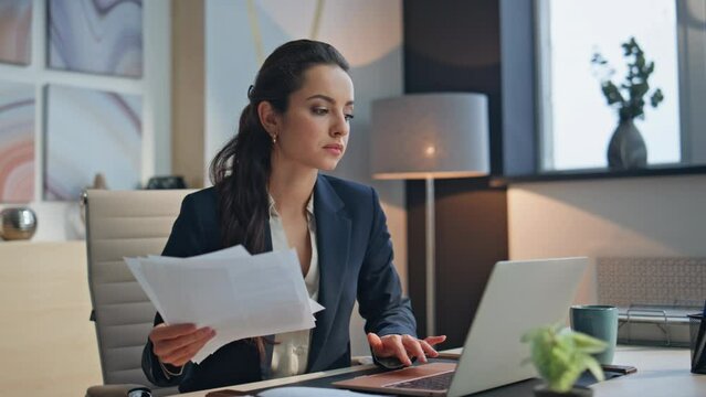 Upset businesswoman holding documents working computer desk at cabinet closeup