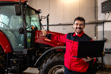 Portrait of experienced tractor serviceman with laptop diagnostic tool.