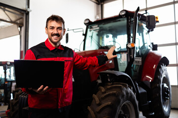 Professional serviceman holding diagnostic tool and repairing tractor.