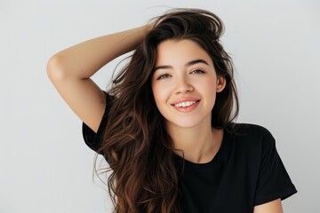 Young woman smiling and looking elegant isolated on a white background in a black t shirt touching her hair