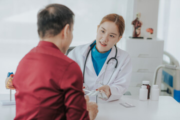 Heart disease, providing advice on heart disease treatment Asian female cardiologist while consulting shows anatomical model of human heart to elderly patient talking about heart disease.