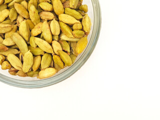 Cardamom pods in glass bowl in the corner on white background, Top view