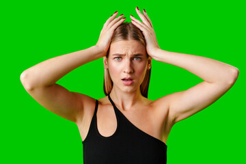 Young Woman Holding Hands Up to Head against green background - obrazy, fototapety, plakaty