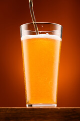 a glass of beer on a wooden stand and a light brown background, pouring beer into a glass, a close view of the object, the beer foams up and bubbles