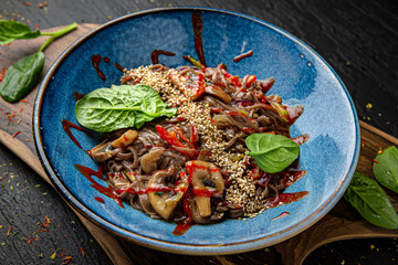 Buckwheat noodles with mushrooms and sweet and sour sauce. Menu for a pub on a dark background. Colorful juicy food photography.