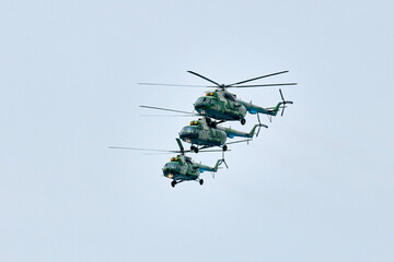 Three Russian military helicopters armed with missiles flies in blue sky, airborne mission of gunships with targeting system performs an aerial maneuvers for military operation, russian aviation