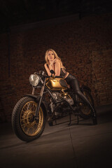 Sexy girl a motorbiker posing near retro style motorcycle.