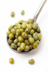 Dry, green mung beans in iron spoon on white background. Close-up