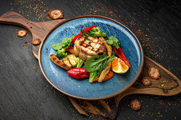 Sturgeon steak with roasted vegetables. Menu for a pub on a dark background. Colorful juicy food photography.