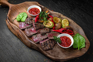 A large plateful of meaty cuts of mildly grilled steak with grilled vegetables. A set for a large...