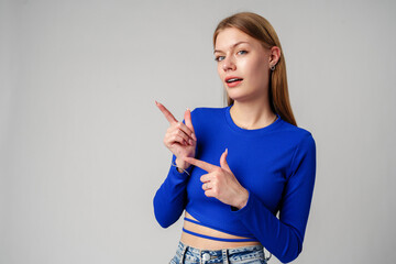 Woman in Blue Top Pointing With Hand Against Neutral Background