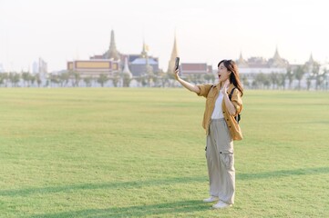 Traveler asian woman in her 30s take a livestream on smartphone while explores Wat Phra Kaew emerald Buddha. Share the wonders of Thai heritage through her journey. - 792476787