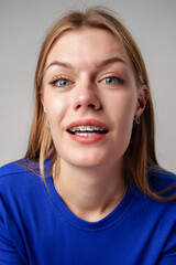 Young Woman With Braces and Blue Shirt on gray background