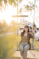 asian woman sitting in swing at camping site.