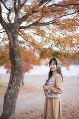 Asian woman in casual dress embraces the fall beauty of Japan, enjoying a holiday filled with smiles, fashion, and vibrant foliage. A cheerful portrait capturing the essence of a vacation. - 792478503