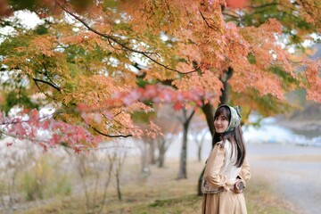 Asian woman in Japan's fall beauty, a cheerful holiday portrait in yellow and red foliage. A journey capturing the essence of nature, fashion, and casual elegance.