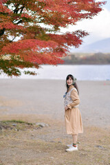 Asian woman in Japan's fall beauty, a cheerful holiday portrait in yellow and red foliage. A journey capturing the essence of nature, fashion, and casual elegance. - 792478525