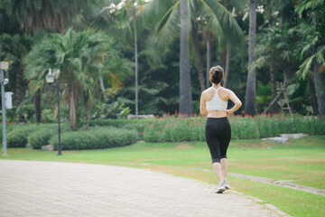 asian woman jogger running in green nature public park.
