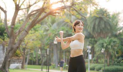 Female sportswoman. Fit young Asian woman with sportswear stretching muscle in park before running and enjoying healthy outdoor. Fitness runner girl in public park. Wellness being concept