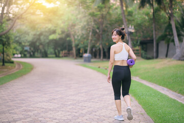 pretty fitness yoga woman walking in the park with yoga mat - 792478941