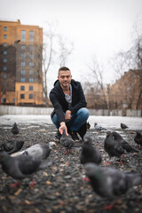 Man feeds pigeons on the spring street of house yard.