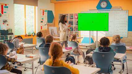 Caring Primary School Teacher Using a TV with Green Screen Display, Explaining an Exercise to a...