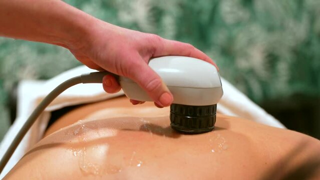 Patient lying on stretcher receiving a shockwave alternative therapy massage in a clinic