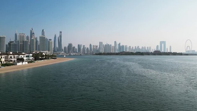 Drone flies over the sea overlooking Dubai and private villas
