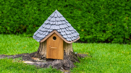 Fototapeta na wymiar A miniature wooden garden gnome house in the middle of a rich green garden. The house. AI Generative