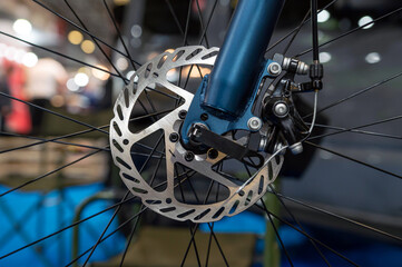 Closeup of a metal brake disc on the front wheel of a mountain bike. - obrazy, fototapety, plakaty