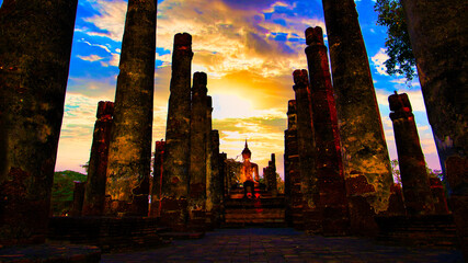 A beautiful sunset is reflected in the pillars of a temple in Sukhothai National Park