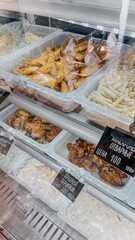 Various delicious food in containers on display in a deli case