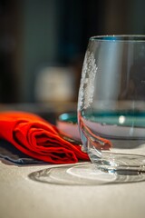 Elegant single wine glass on a table with a red cloth napkin beside it