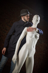 Man in the classic suit is posing with a white mannequin.