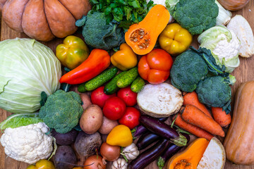 Various vegetables are laid out on a wooden table. Large assortment of vegetables food. pumpkin cabbage broccoli pepper tomatoes carrots and others