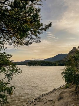 Calm lake Borovoe with a rocky shore and distant mountains at sunset