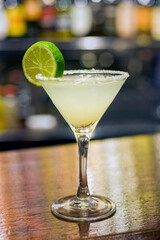 daiquiri cocktail on wooden bar and display case background with bottles